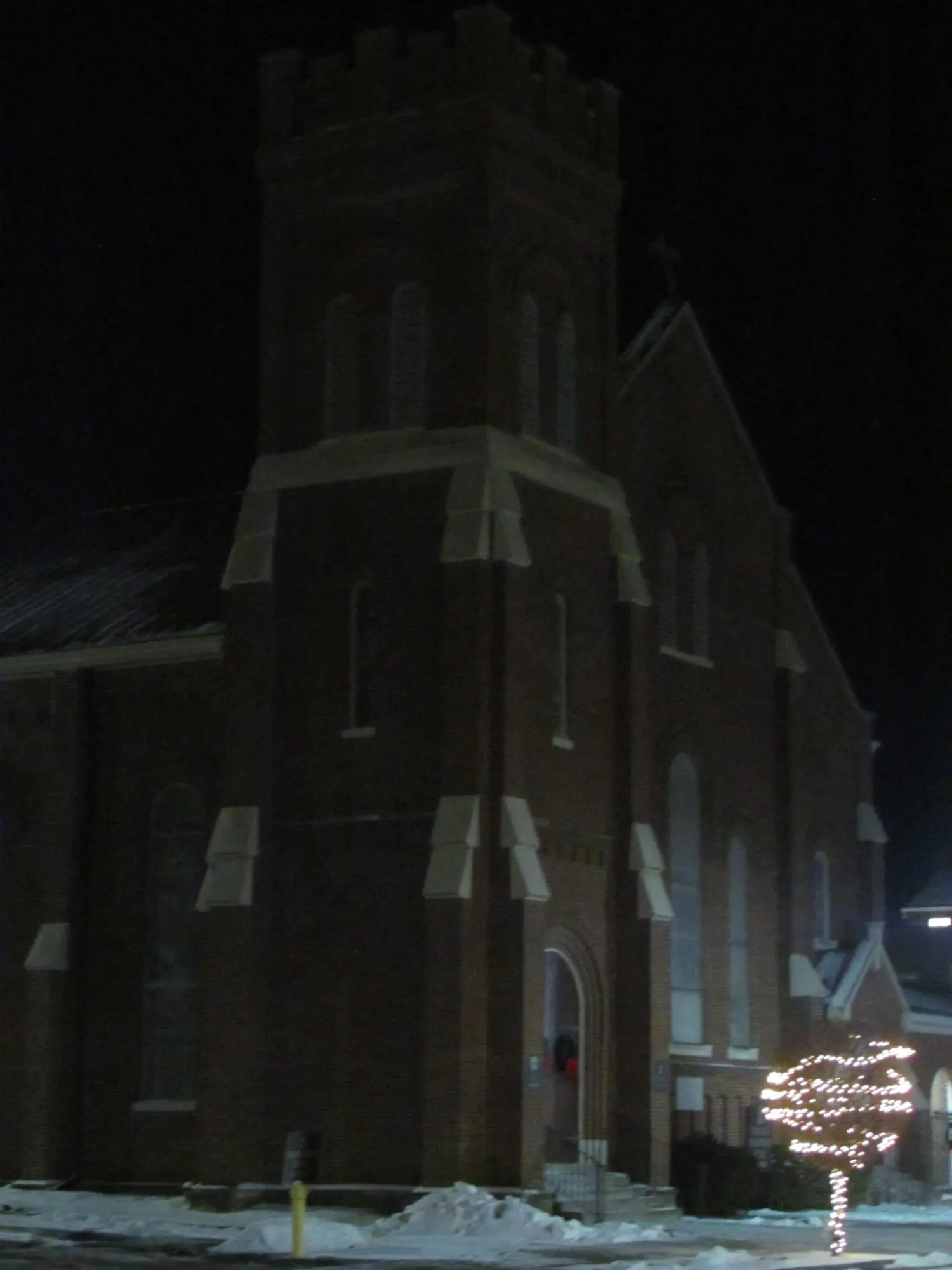 A brick church tower at night in the snow
