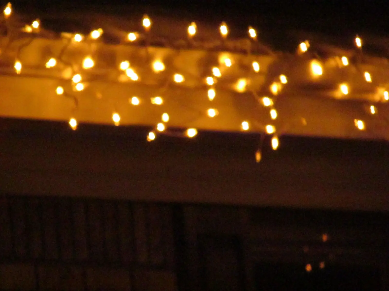 Icicle lights along a roof, blurred