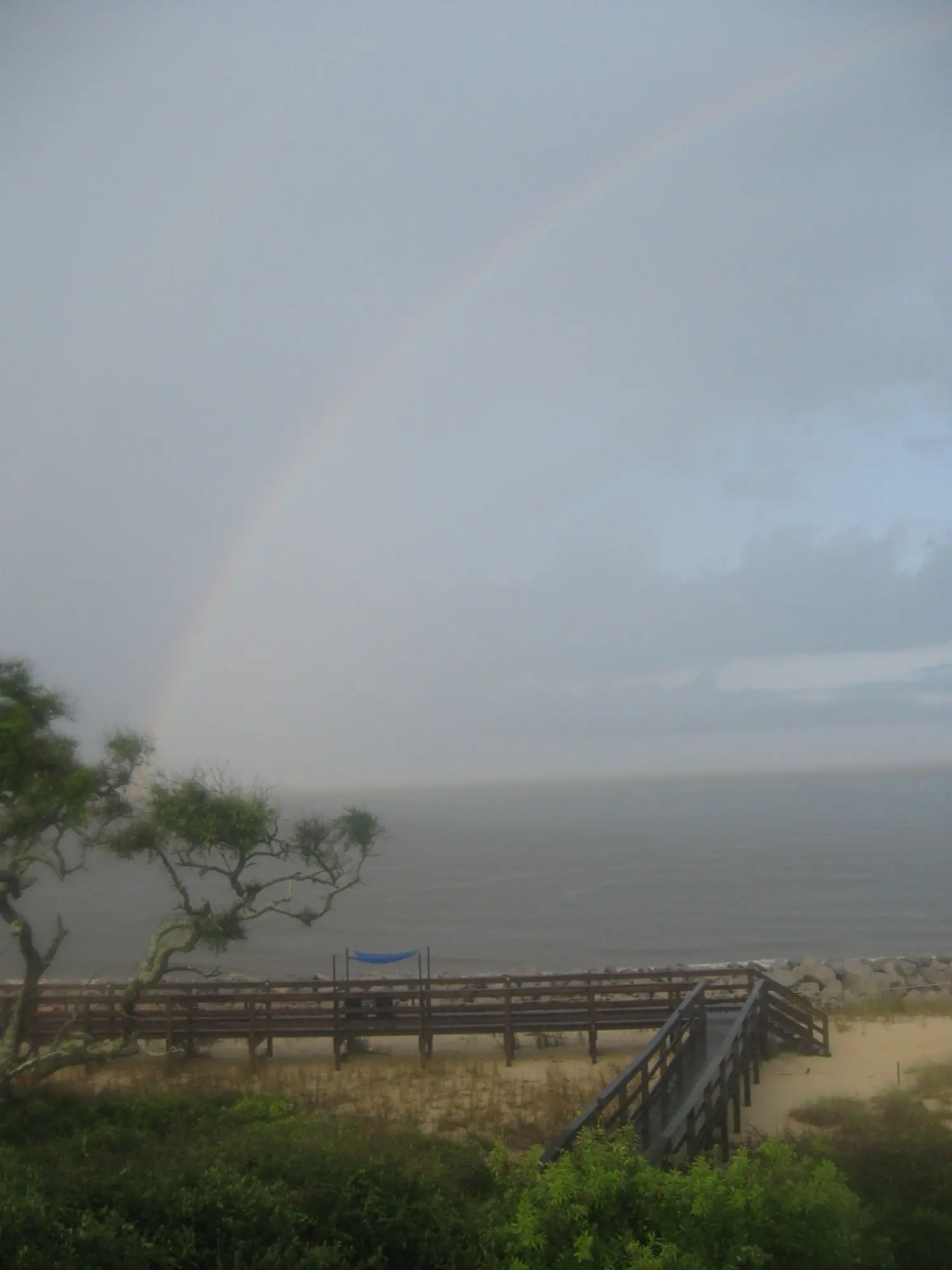A faint rainbow over the sea from a boardwalk